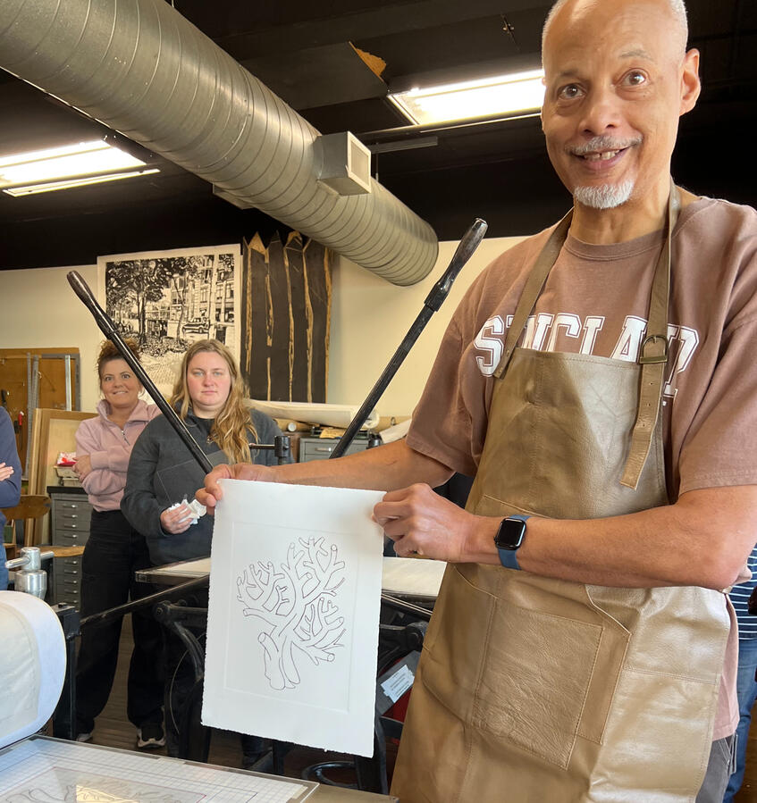 Man with apron holding a print he's just made